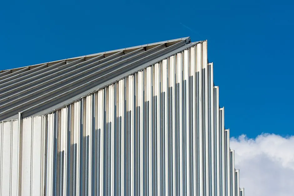 Low angle shot of a modern building with a corrugated steel facade against a clear blue sky.
