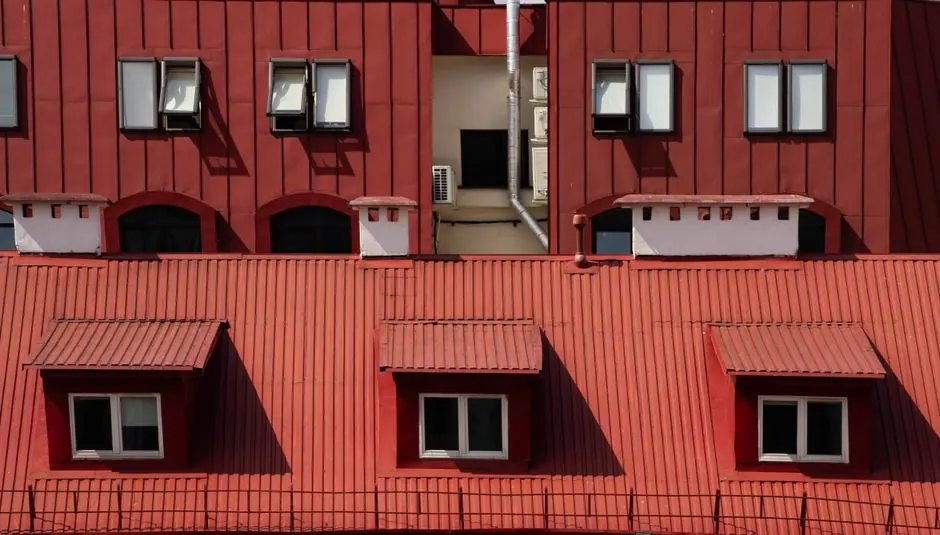 Red building facade featuring windows and air conditioning units, showcasing urban architecture.